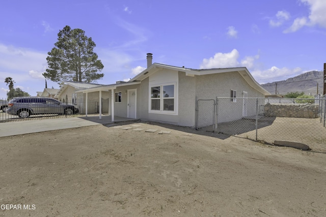 ranch-style house with stucco siding, a gate, fence, and driveway