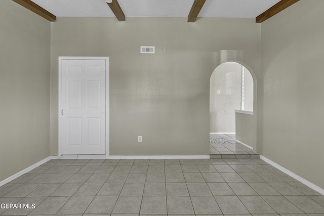 tiled empty room with arched walkways, beamed ceiling, visible vents, and baseboards