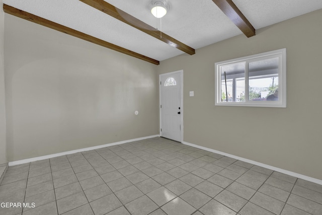 foyer with beamed ceiling, a textured ceiling, baseboards, and light tile patterned flooring