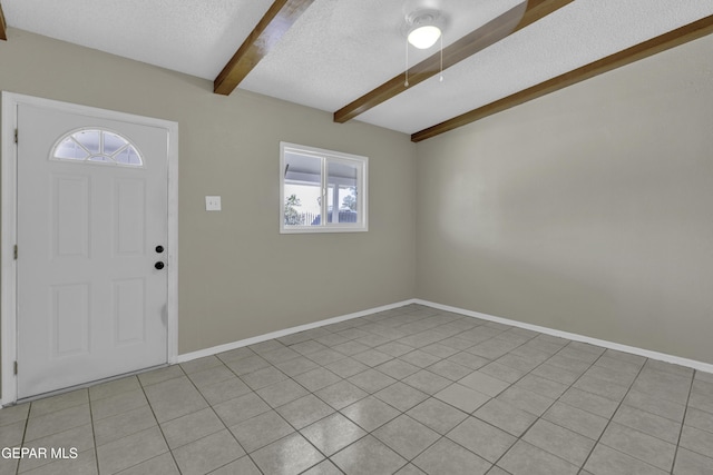 tiled foyer featuring baseboards, beam ceiling, and a textured ceiling