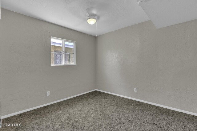 carpeted spare room featuring a ceiling fan and baseboards