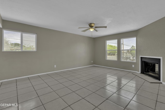 unfurnished living room with baseboards, a ceiling fan, tile patterned flooring, and a fireplace