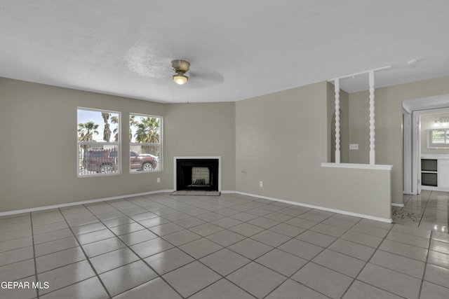 unfurnished living room featuring tile patterned floors, a ceiling fan, baseboards, and a fireplace