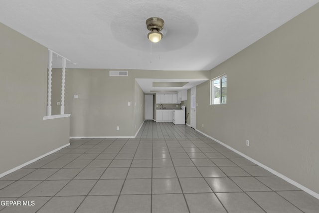 unfurnished living room with visible vents, a ceiling fan, baseboards, and light tile patterned floors