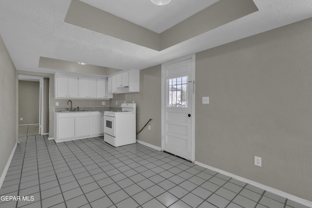 kitchen featuring light countertops, a sink, baseboards, white gas range oven, and white cabinetry