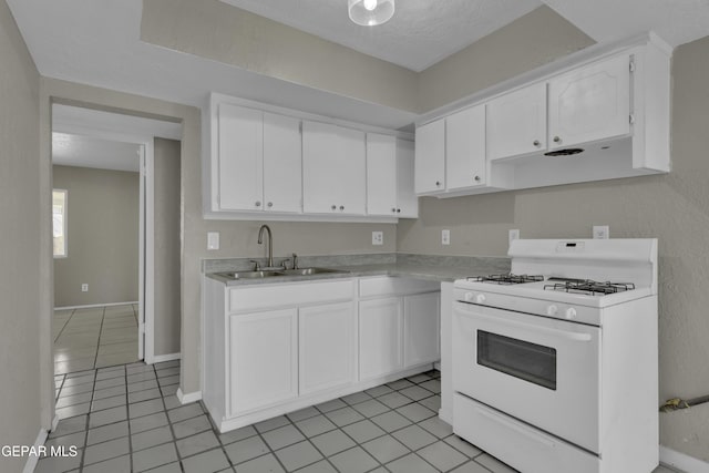 kitchen featuring white gas stove, light countertops, white cabinets, and a sink