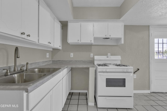 kitchen featuring white range with gas cooktop, a sink, white cabinetry, and light tile patterned floors