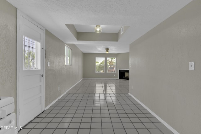 unfurnished living room featuring a fireplace, a textured wall, a textured ceiling, and ceiling fan
