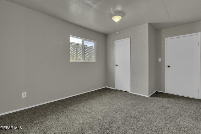 carpeted spare room with ceiling fan and baseboards