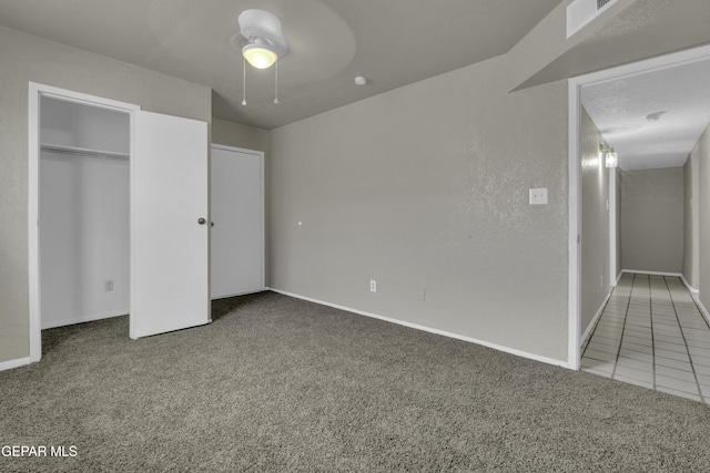 unfurnished bedroom with tile patterned flooring, a ceiling fan, carpet floors, a closet, and baseboards