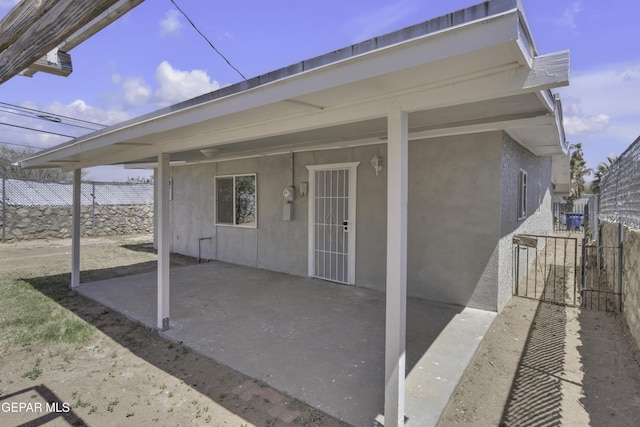 exterior space with stucco siding, fence, and a patio area