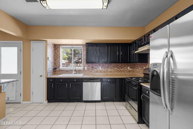 kitchen featuring under cabinet range hood, light countertops, a sink, tasteful backsplash, and appliances with stainless steel finishes