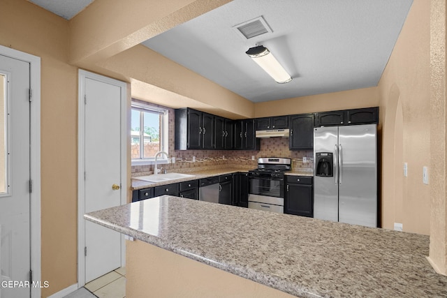 kitchen with under cabinet range hood, stainless steel appliances, visible vents, a sink, and a peninsula