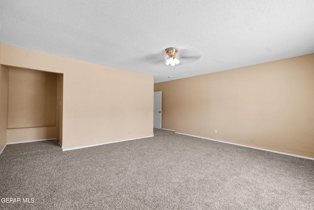 spare room with ceiling fan, baseboards, a textured ceiling, and carpet