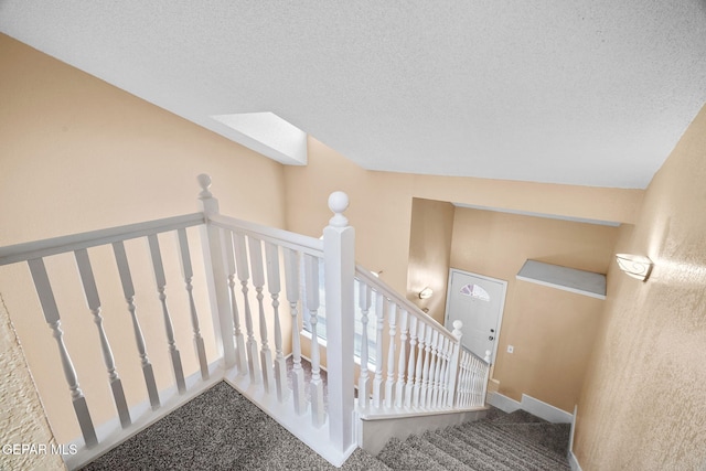 stairway with carpet flooring and a textured ceiling