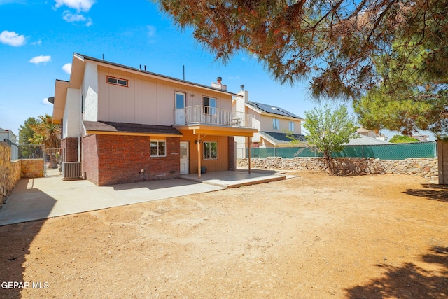 rear view of house with a chimney, a fenced backyard, a balcony, a patio, and brick siding
