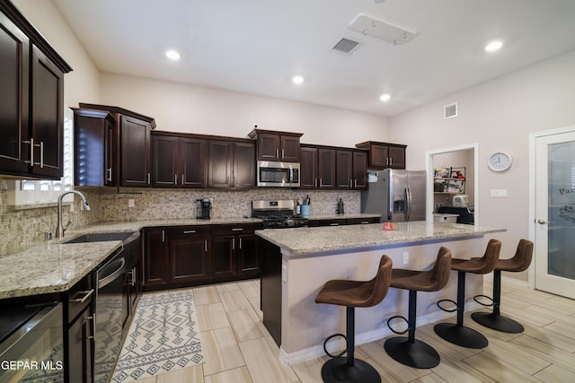 7825 Enchanted Ridge Dr, El Paso, TX 79911 - kitchen with stainless steel appliances, visible vents, decorative backsplash, and a kitchen island