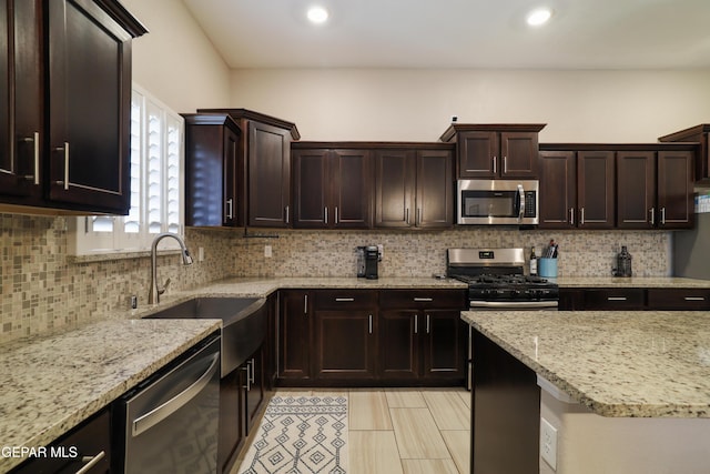 7825 Enchanted Ridge Dr, El Paso, TX 79911 - kitchen with light stone counters, a sink, dark brown cabinetry, stainless steel appliances, and backsplash
