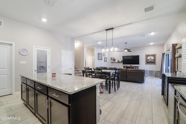 7825 Enchanted Ridge Dr, El Paso, TX 79911 - kitchen featuring a ceiling fan, open floor plan, decorative light fixtures, light stone countertops, and visible vents
