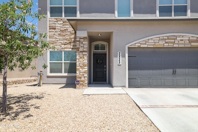 7825 Enchanted Ridge Dr, El Paso, TX 79911 - property entrance featuring stucco siding, an attached garage, driveway, and stone siding
