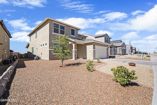 view of front of property with driveway, stone siding, central air condition unit, an attached garage, and stucco siding