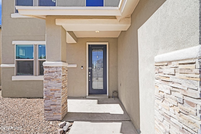 entrance to property featuring stucco siding and stone siding