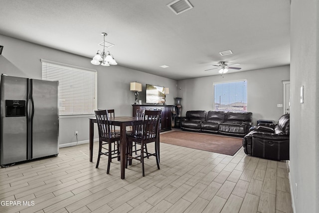dining room featuring ceiling fan with notable chandelier, visible vents, baseboards, and light wood-type flooring