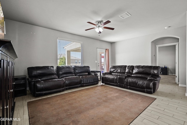 living area with arched walkways, visible vents, a ceiling fan, and wood finished floors