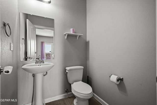 bathroom featuring toilet, a sink, wood finished floors, and baseboards