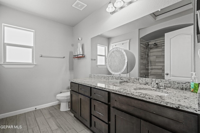 full bathroom with tiled shower, toilet, vanity, baseboards, and visible vents