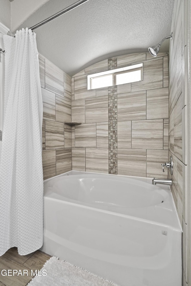 bathroom with shower / bath combo with shower curtain and a textured ceiling