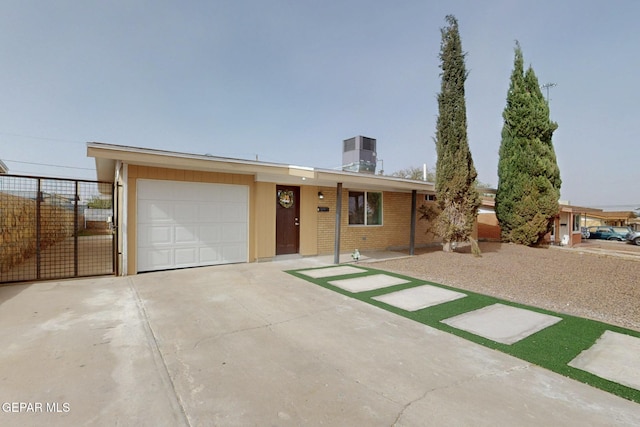 single story home featuring fence, cooling unit, concrete driveway, brick siding, and a garage