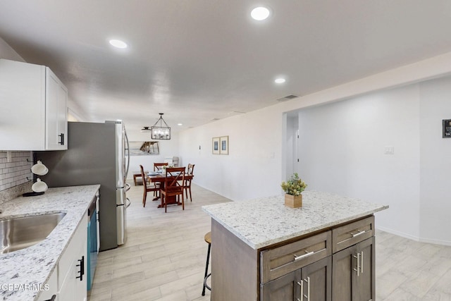 kitchen with white cabinetry, tasteful backsplash, a sink, and visible vents