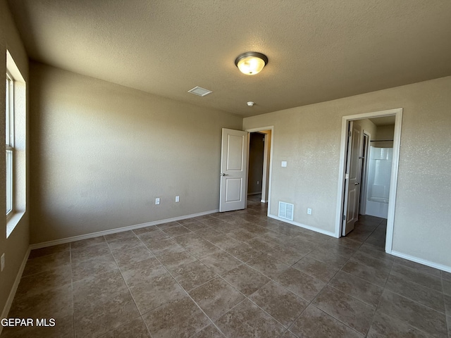 312 Via Cumbre Linda Cir, El Paso, TX 79928 - unfurnished bedroom featuring dark tile patterned floors, baseboards, visible vents, and a textured ceiling