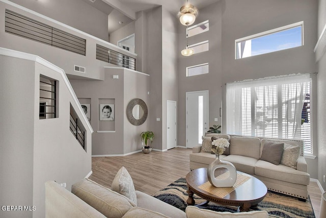living room featuring baseboards, wood finished floors, visible vents, and plenty of natural light