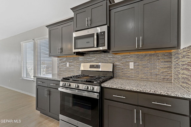 1205 Night Sky St, Horizon City, TX 79928 - kitchen with stainless steel appliances, backsplash, light wood-style floors, light stone countertops, and baseboards