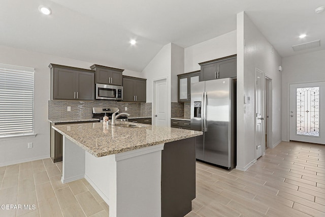 1205 Night Sky St, Horizon City, TX 79928 - kitchen featuring light stone counters, backsplash, a sink, a center island with sink, and appliances with stainless steel finishes