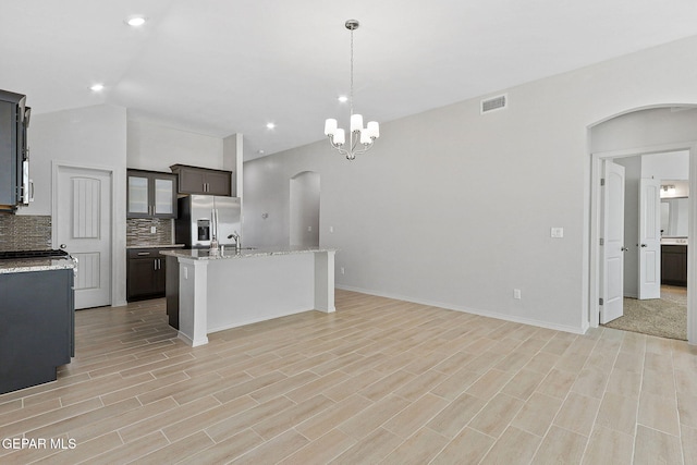 1205 Night Sky St, Horizon City, TX 79928 - kitchen featuring arched walkways, stainless steel fridge, visible vents, backsplash, and an island with sink