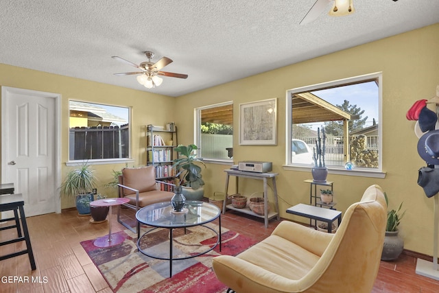 sitting room featuring baseboards, wood finished floors, a textured ceiling, and ceiling fan