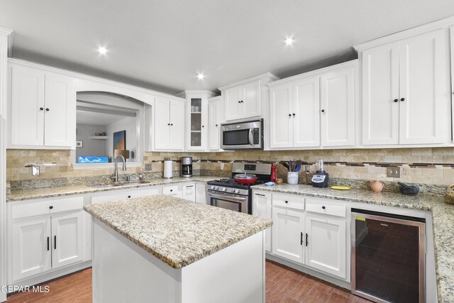 kitchen with white cabinets, beverage cooler, stainless steel appliances, backsplash, and a sink