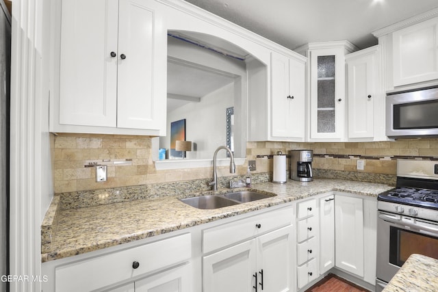 kitchen with appliances with stainless steel finishes, white cabinetry, and a sink