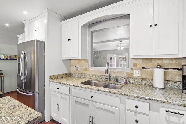 kitchen featuring a sink, tasteful backsplash, white cabinetry, light stone counters, and stainless steel refrigerator with ice dispenser