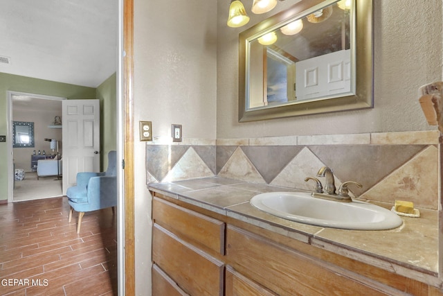 bathroom with tasteful backsplash, vanity, wood finished floors, and visible vents