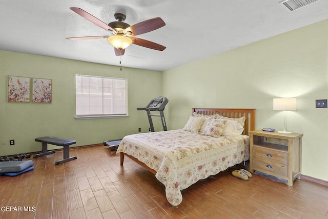 bedroom with wood finished floors, visible vents, baseboards, and ceiling fan