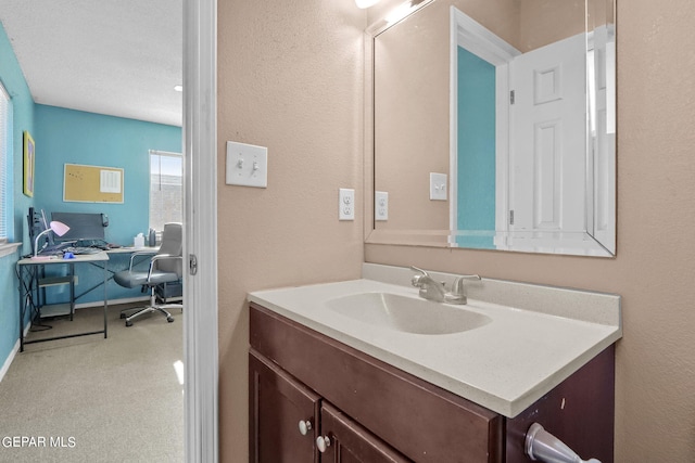 bathroom featuring a textured wall and vanity
