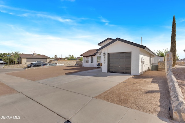 view of front facade with a garage, brick siding, central AC unit, and driveway