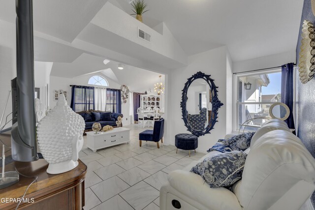 living area featuring vaulted ceiling, visible vents, marble finish floor, and a chandelier