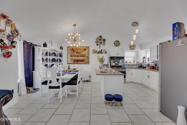 kitchen featuring white cabinetry, light stone counters, under cabinet range hood, appliances with stainless steel finishes, and hanging light fixtures
