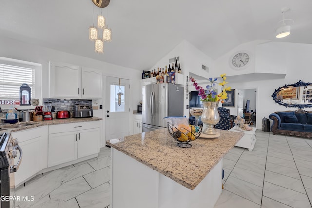 kitchen with lofted ceiling, plenty of natural light, marble finish floor, and appliances with stainless steel finishes