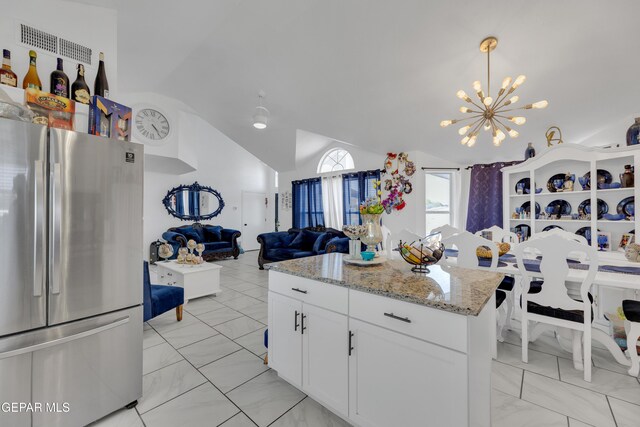 kitchen featuring white cabinets, lofted ceiling, an inviting chandelier, freestanding refrigerator, and open floor plan
